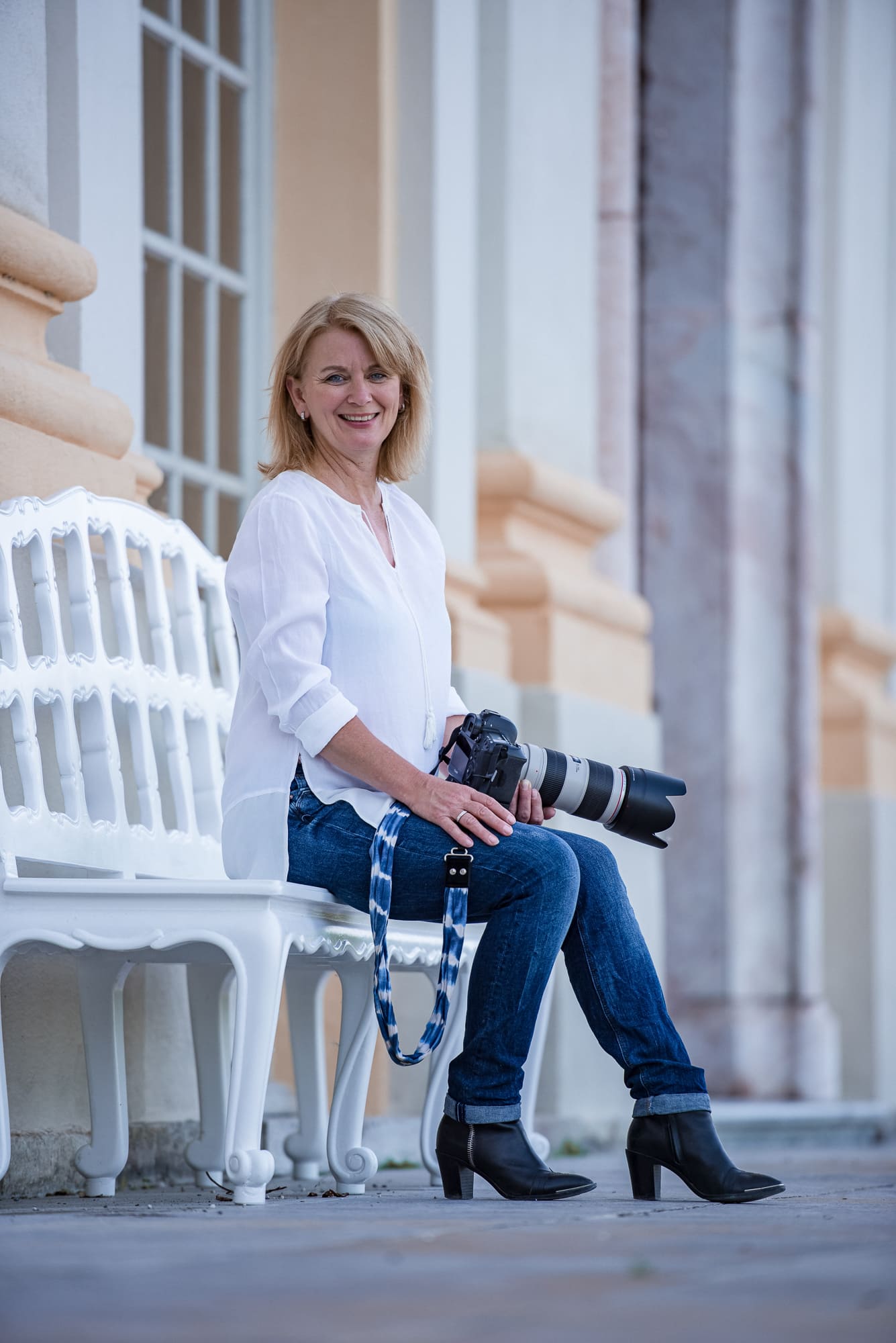 Tierfotografin, eine Fotografin sitzt mit ihrer Kamera auf einer Bank.