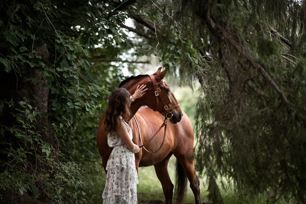 Frau mit Pferd unter den Bäumen